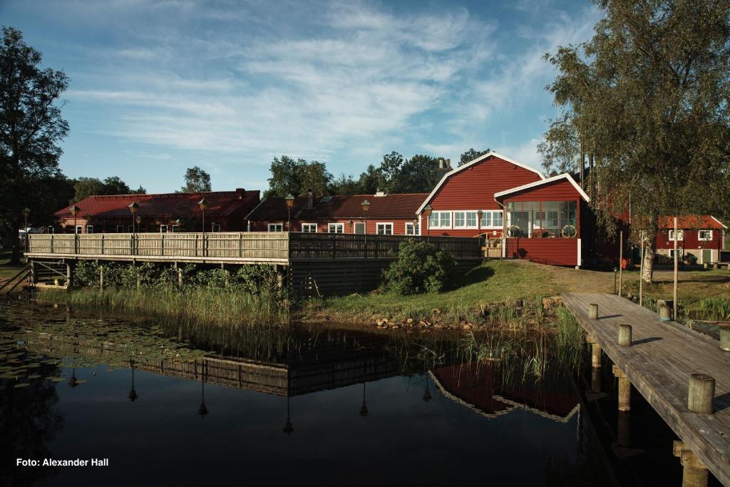 RolfstorpÅkulla Outdoor Resort的一座红房子,靠近一座有桥的湖泊