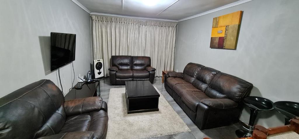 约翰内斯堡Executive 2 bed Apartment, free WIFI and DSTV的客厅配有皮革家具和平面电视