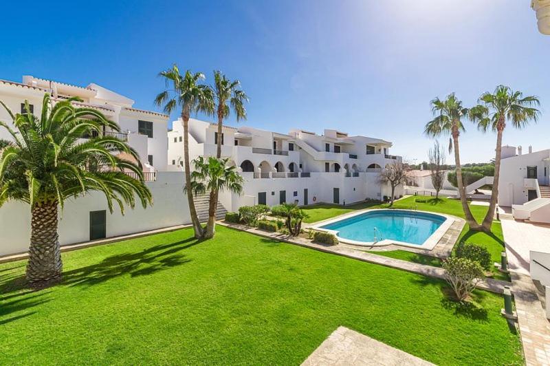 桑帕克Apartamento Albatros-Son Parc Menorca的一座大型白色建筑,设有一座带游泳池的庭院