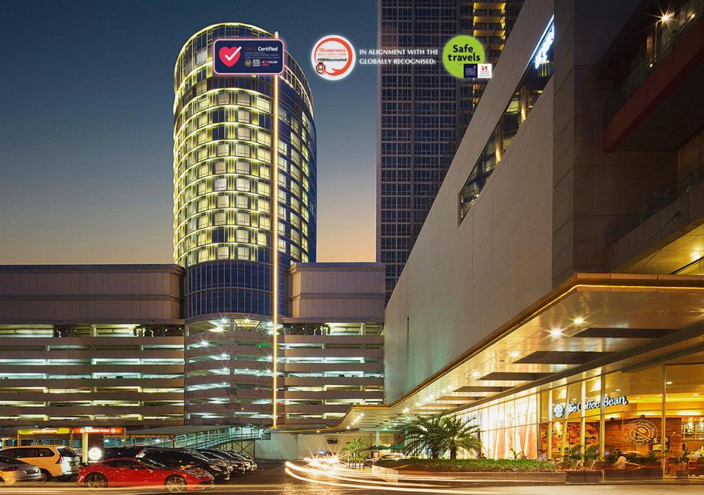 泗水Hotel Ciputra World Surabaya managed by Swiss-Belhotel International的停车场内有车辆停放的高楼