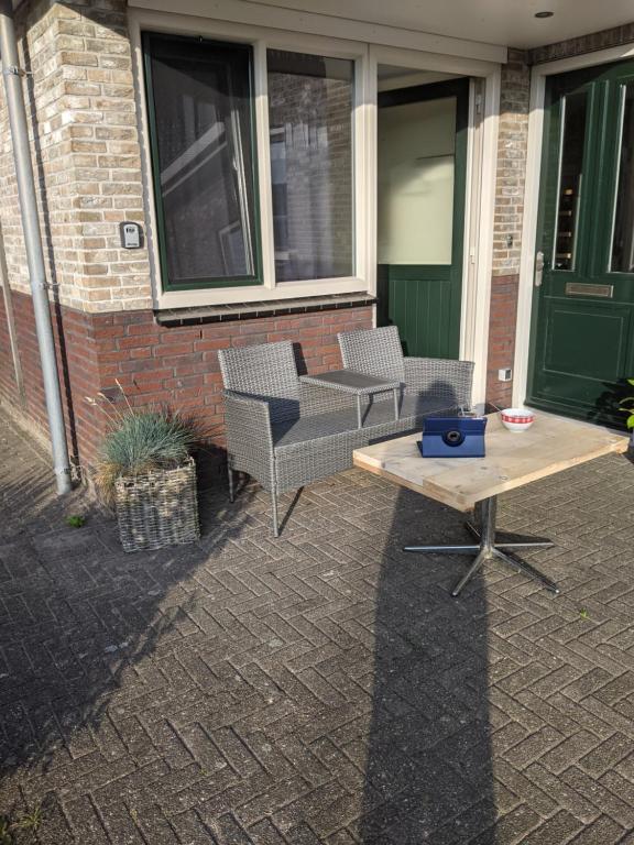 OosterendLogies21 Texel的大楼前的天井配有2把椅子和1张桌子