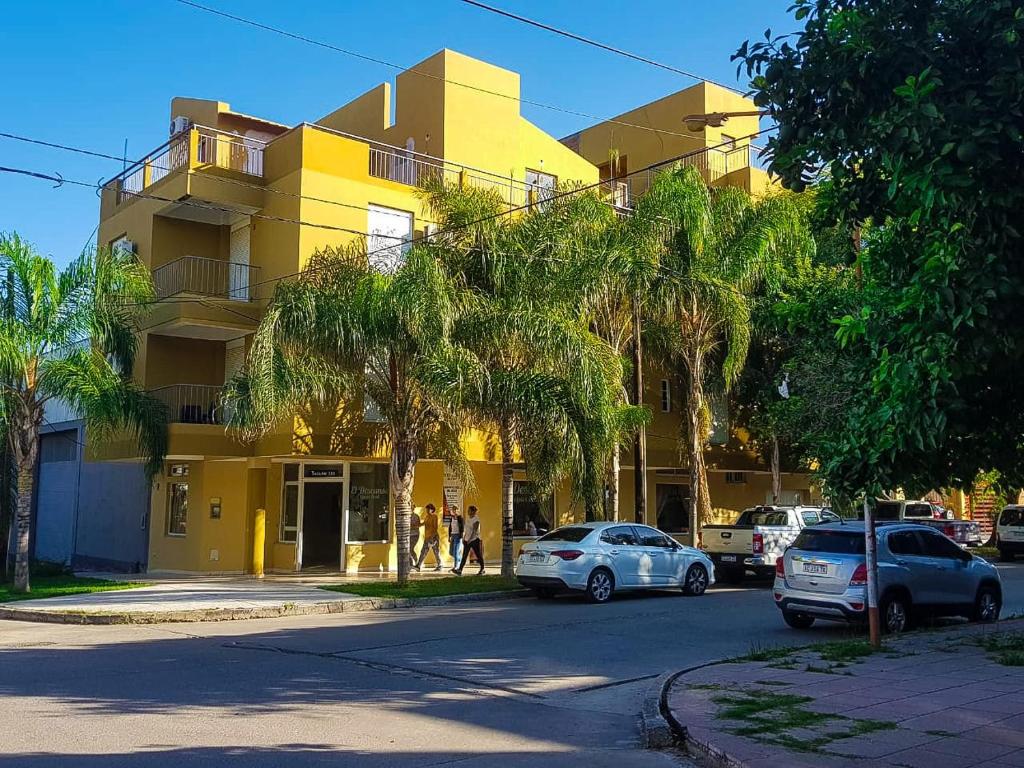 特尔马斯德里奥翁多El Descanso Hotel的一座黄色的建筑,前面有汽车停放