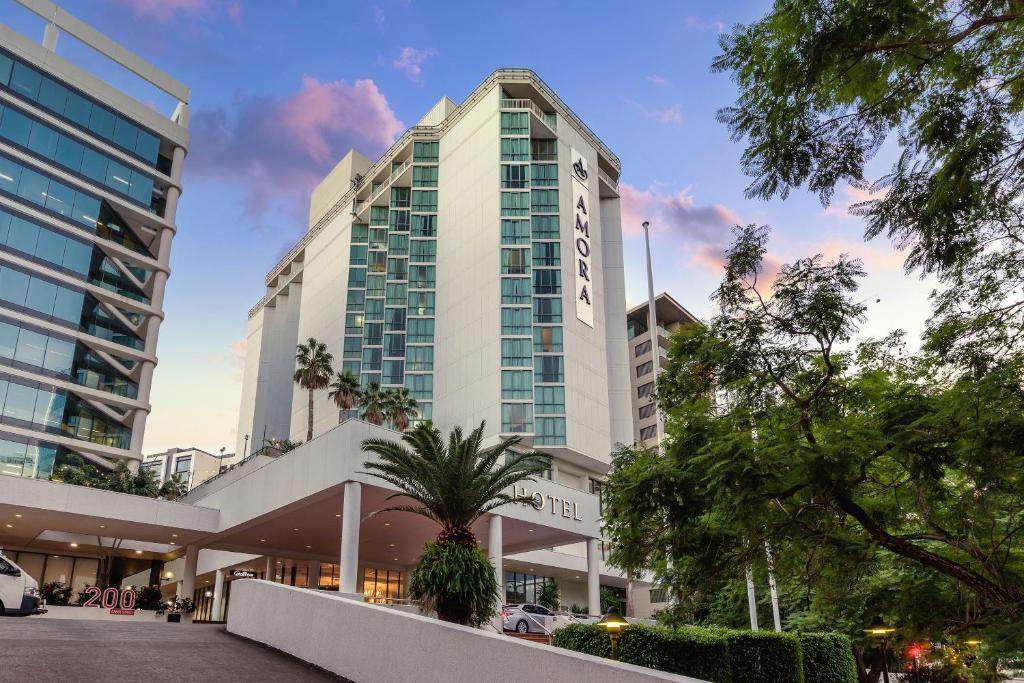 布里斯班Amora Hotel Brisbane的一座高大的白色建筑,前面有一棵棕榈树