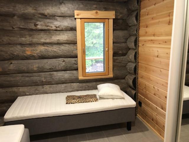 科拉里Kojamopirtit的木制客房的一张床位,设有窗户