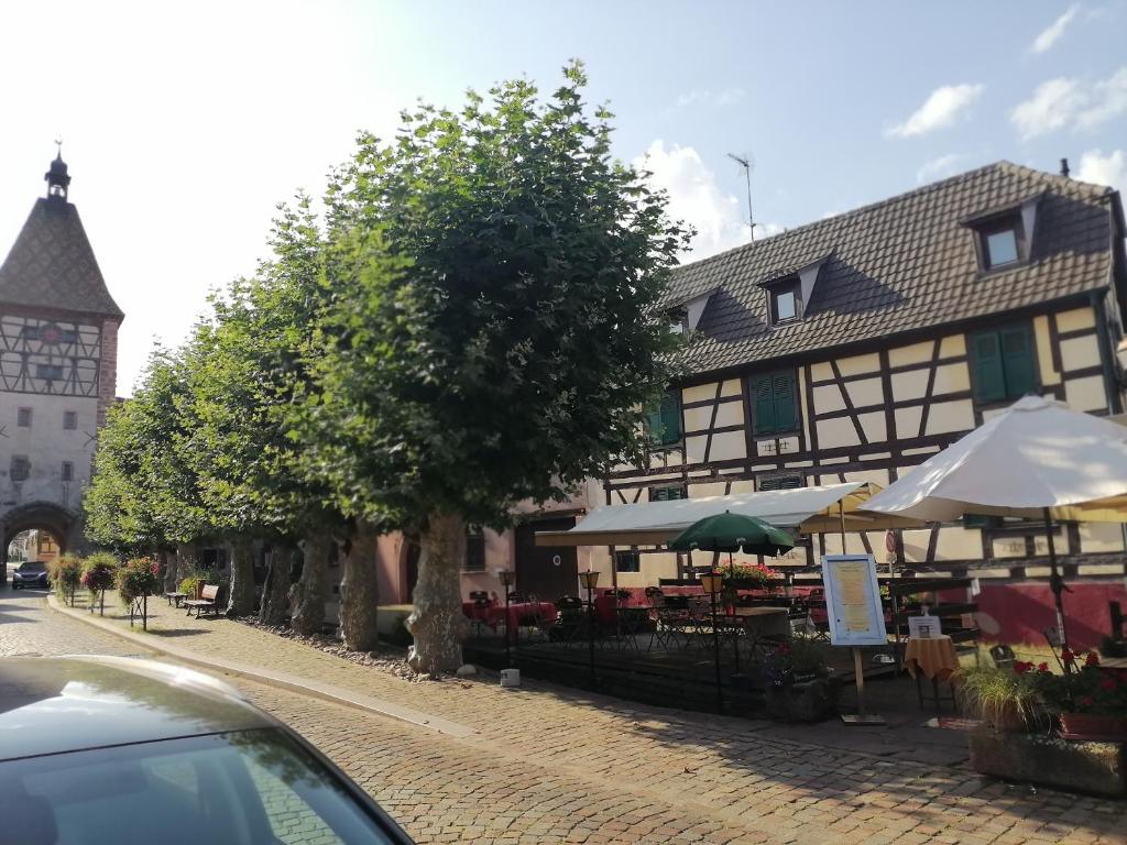 贝格海姆Gites Aux Fines Bulles d'Alsace SPA privatif en supplément的街道上带桌子和遮阳伞的建筑