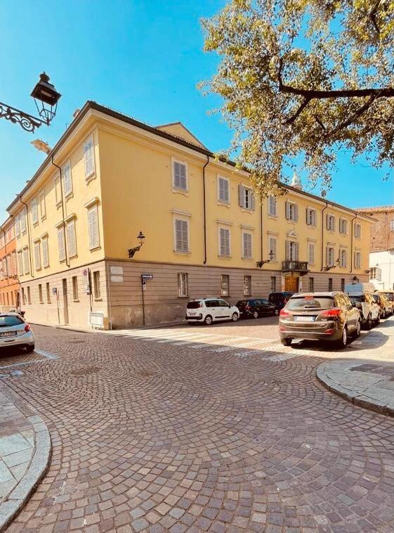 帕尔马Palazzo Borgocolonne Apartments的一座黄色的大建筑,停车场有车辆停放