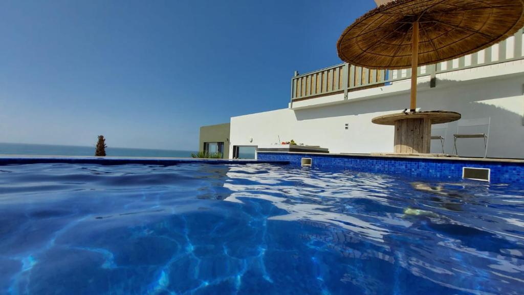 沃利迪耶Maison de plage avec piscine et vue sur mer的一座带遮阳伞的游泳池以及一座建筑