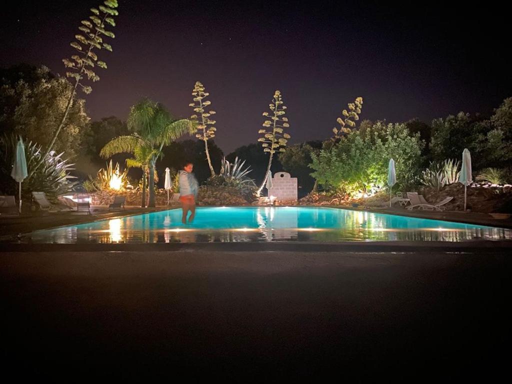 奥斯图尼La Monacedda - Country Boutique Apartments - Villa Laura Ostuni的夜间站在游泳池旁的人