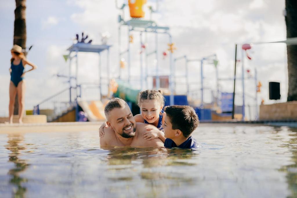 黄金海岸Sea World Resort的游泳池里的一个男人和两个男孩