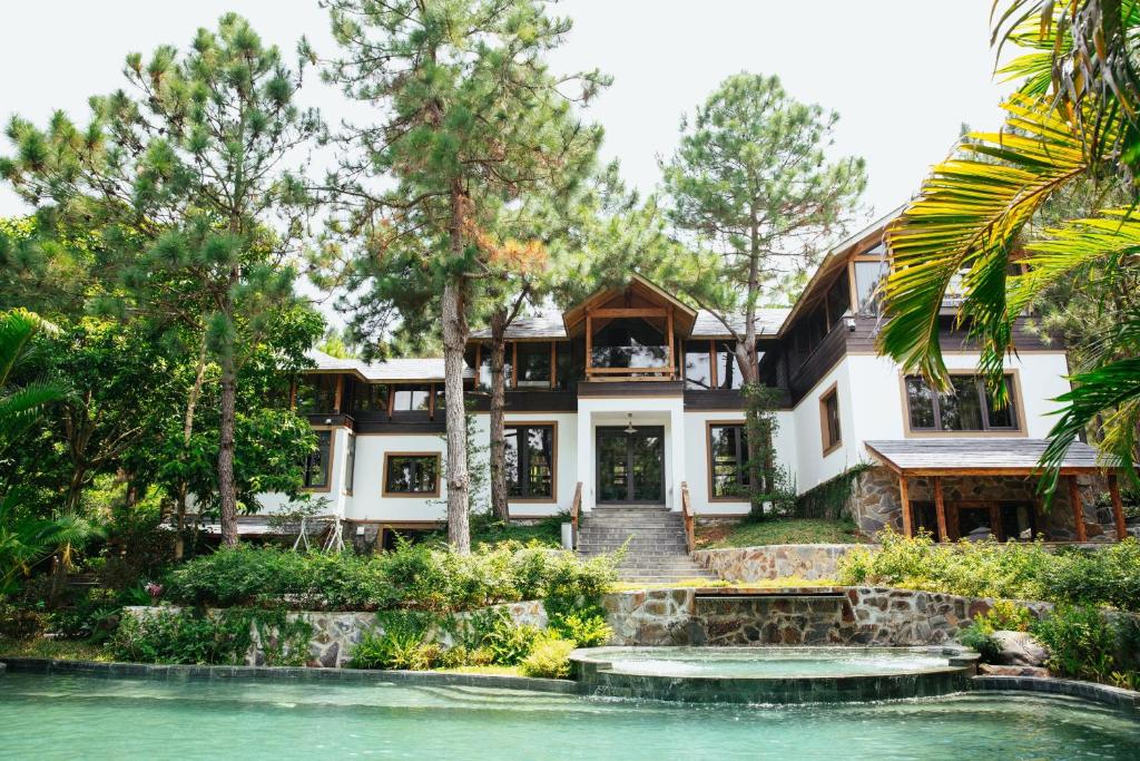 河内AMAYA HOME - Lodge, Spa & Restaurant的前面有池塘的房子