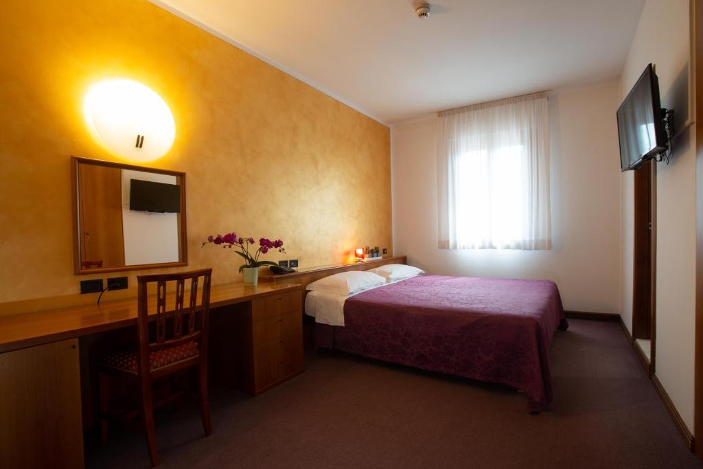 科内利亚诺西玛酒店的酒店客房配有一张床、一张书桌和一台电视。
