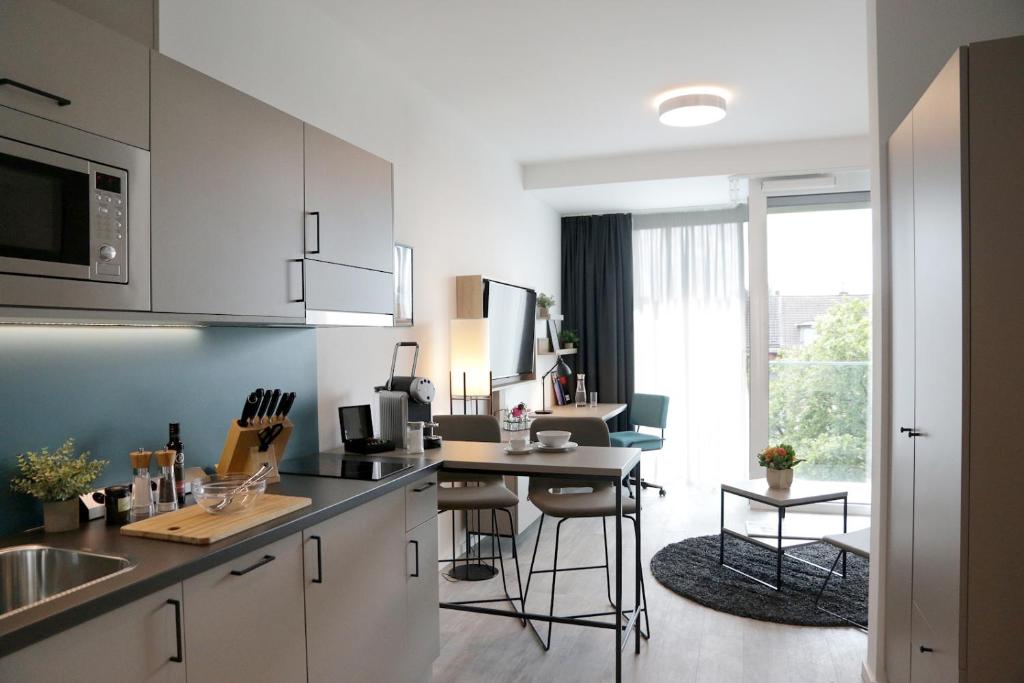 多特蒙德PM-AM Apartments GmbH的厨房配有白色橱柜和桌椅