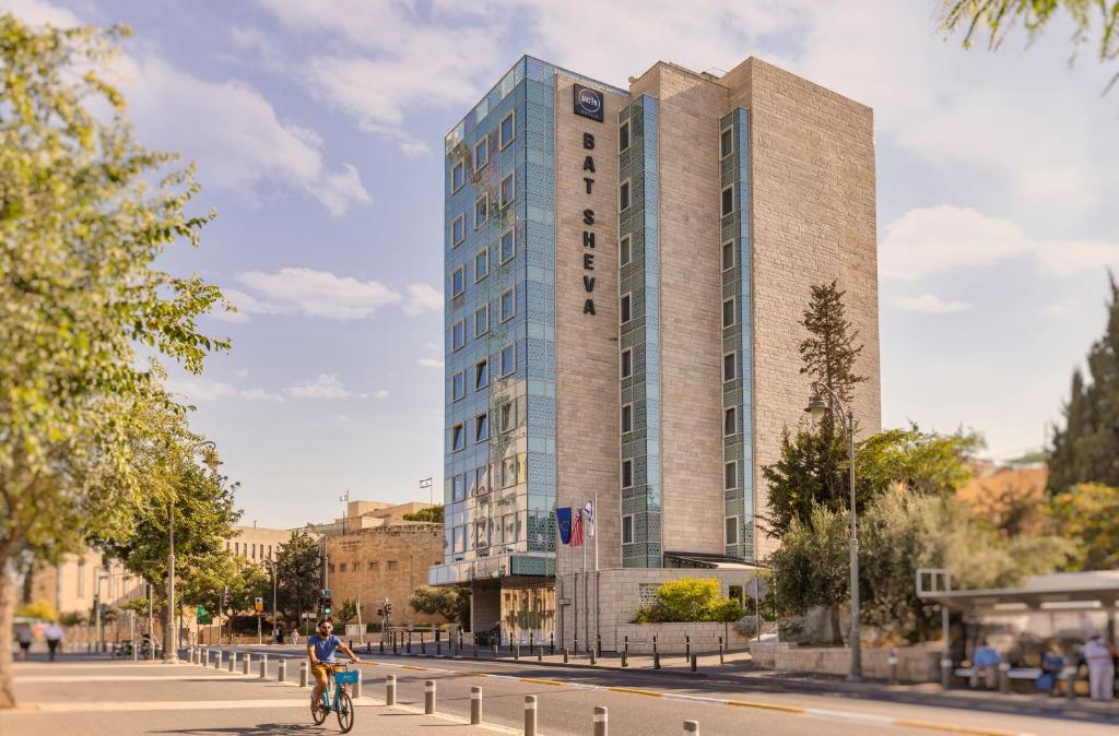 耶路撒冷Bat Sheva Jerusalem by Jacob Hotels的骑着自行车在高楼前的人
