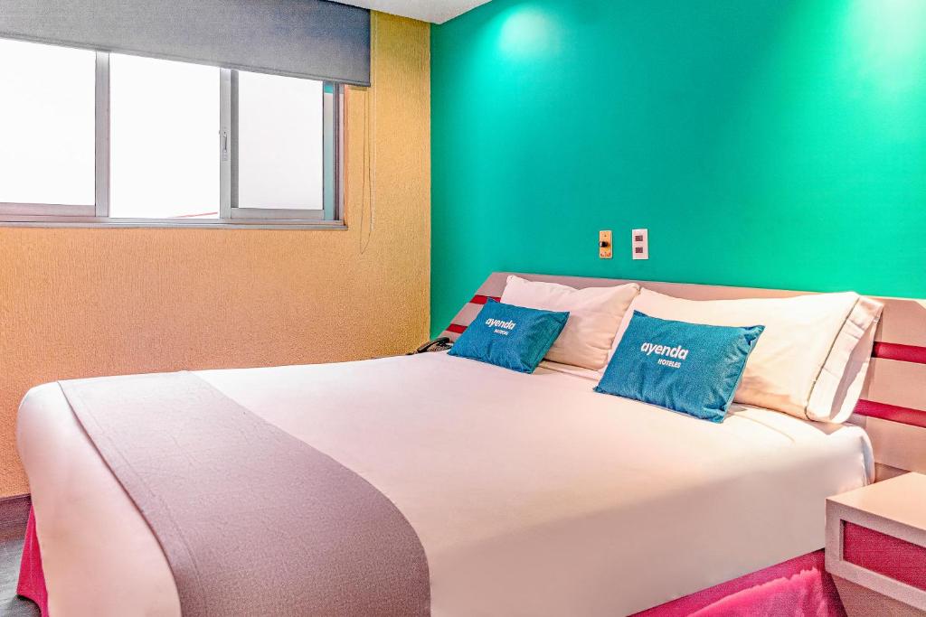 墨西哥城Ayenda Frida Costa Azul的卧室配有带蓝色枕头的大型白色床