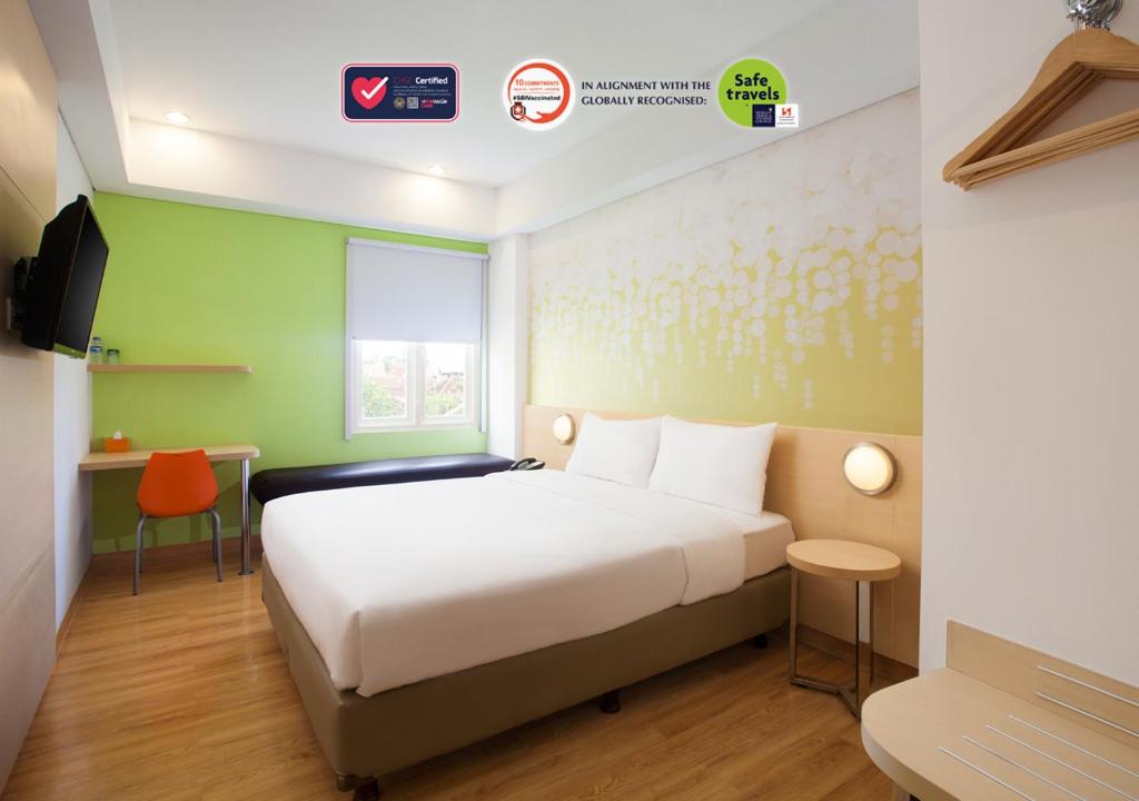 日惹Zest Yogyakarta by Swiss-Belhotel International的一间酒店客房,配有一张床和一台电视