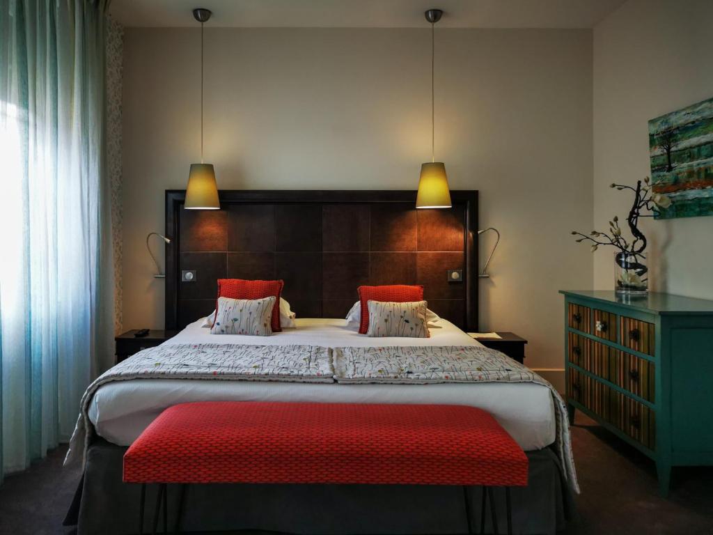 布雷斯地区布尔格金格里芬酒店的一间卧室配有一张大床和红色长凳