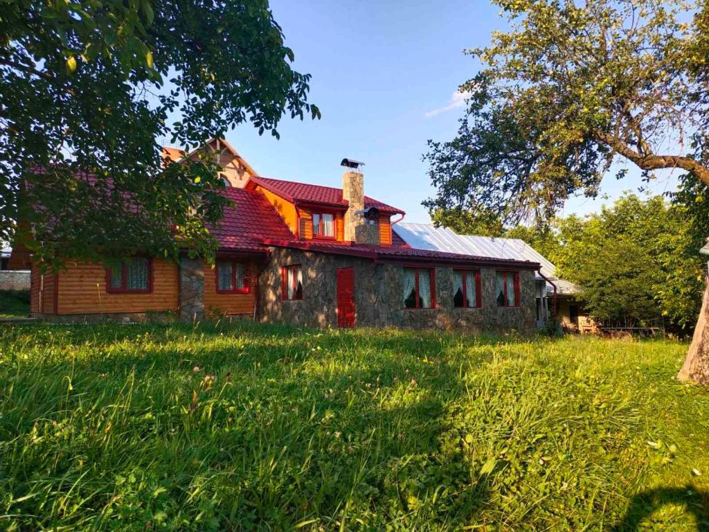 DilyatynБердо-Хауз的一座位于田野的红色屋顶的旧房子