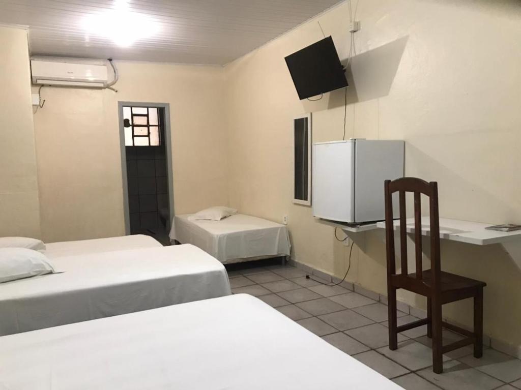 波多韦柳Porto Seguro Hotel - Porto Velho的客房设有两张床、一张桌子和一把椅子。