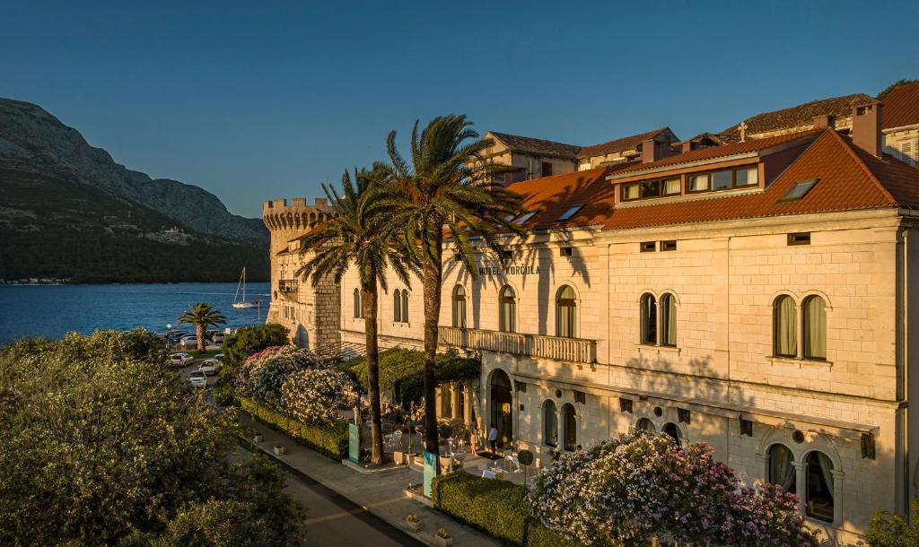 科尔丘拉Aminess Korcula Heritage Hotel的水边有棕榈树的建筑