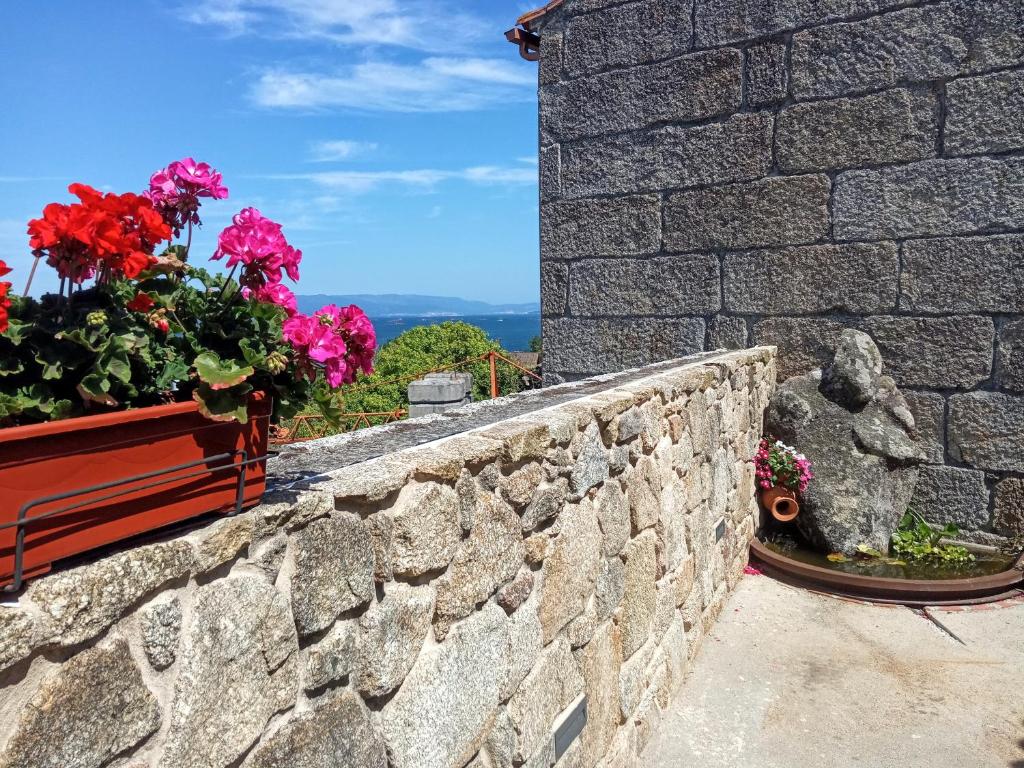 格罗韦O Iniño casita rural costera的石头挡墙,上面有鲜花