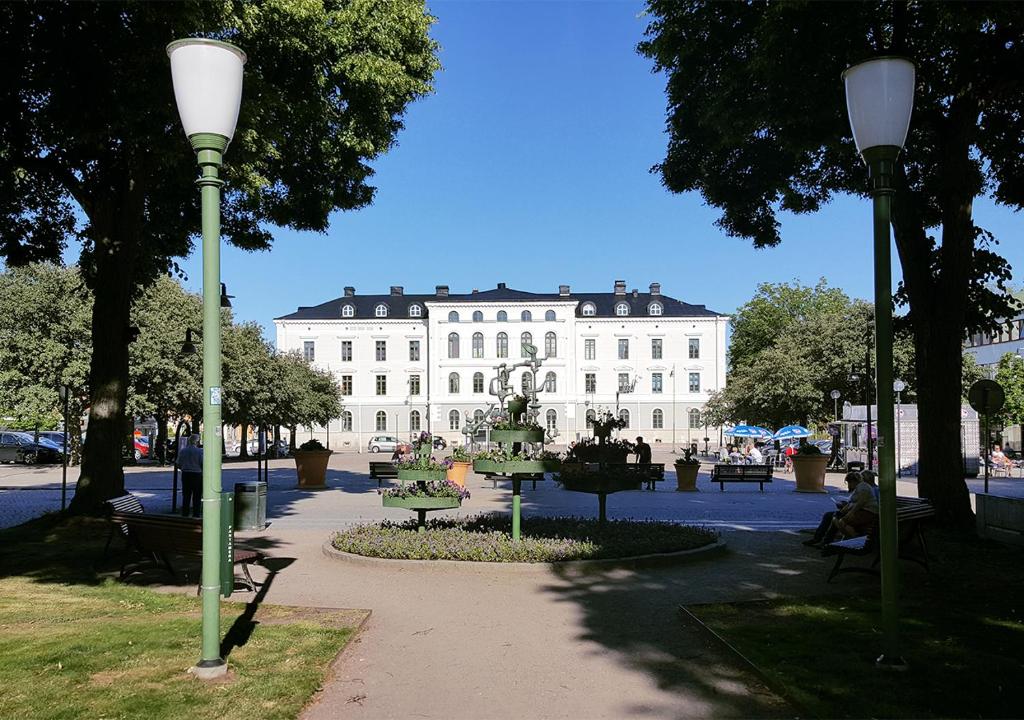 玛丽斯塔德Vänerport Stadshotell i Mariestad的一座大型白色建筑,公园内有雕像