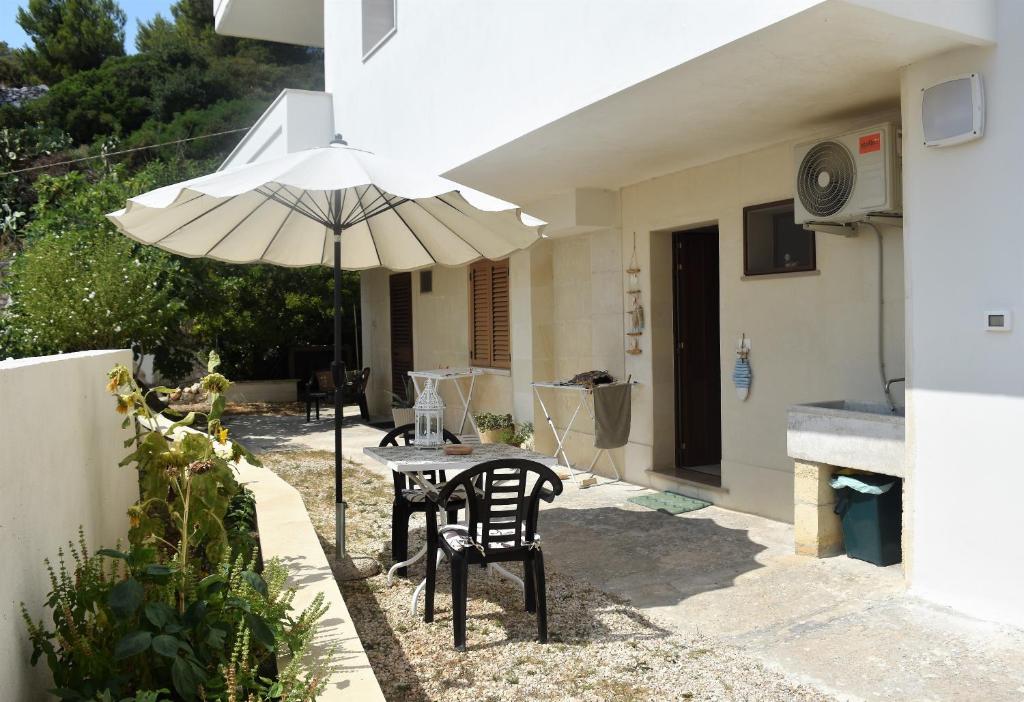 莱切省卡斯特罗Casa vacanze Pesce azzurro的一个带桌子和遮阳伞的庭院