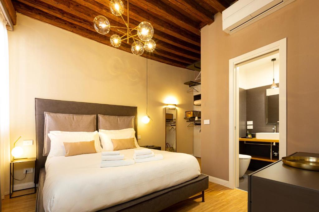 威尼斯Fraivolti apartment的卧室配有一张带吊灯的大型白色床。