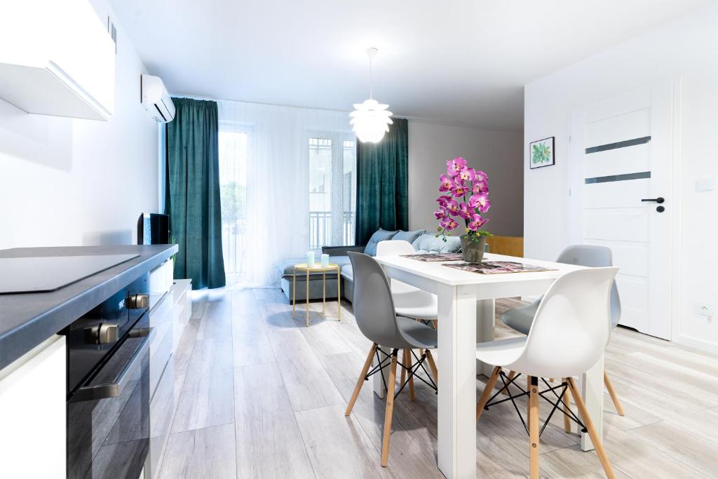 莱格尼察Apartament Uroczy的厨房以及带白色桌椅的用餐室。
