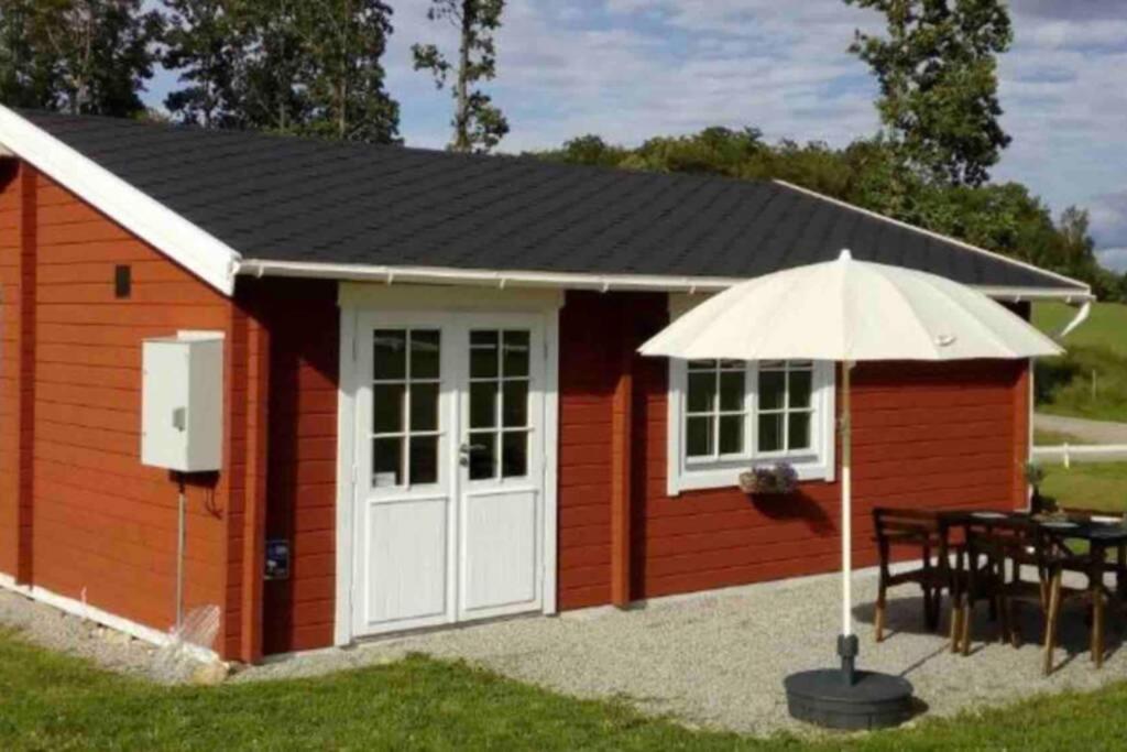 海斯勒霍尔姆Cozy Cottage near lake的红色的棚子,配有桌子和雨伞