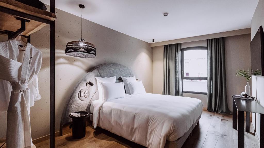 比亚里茨Le Garage Biarritz Hôtel的卧室设有一张白色大床和一扇窗户。