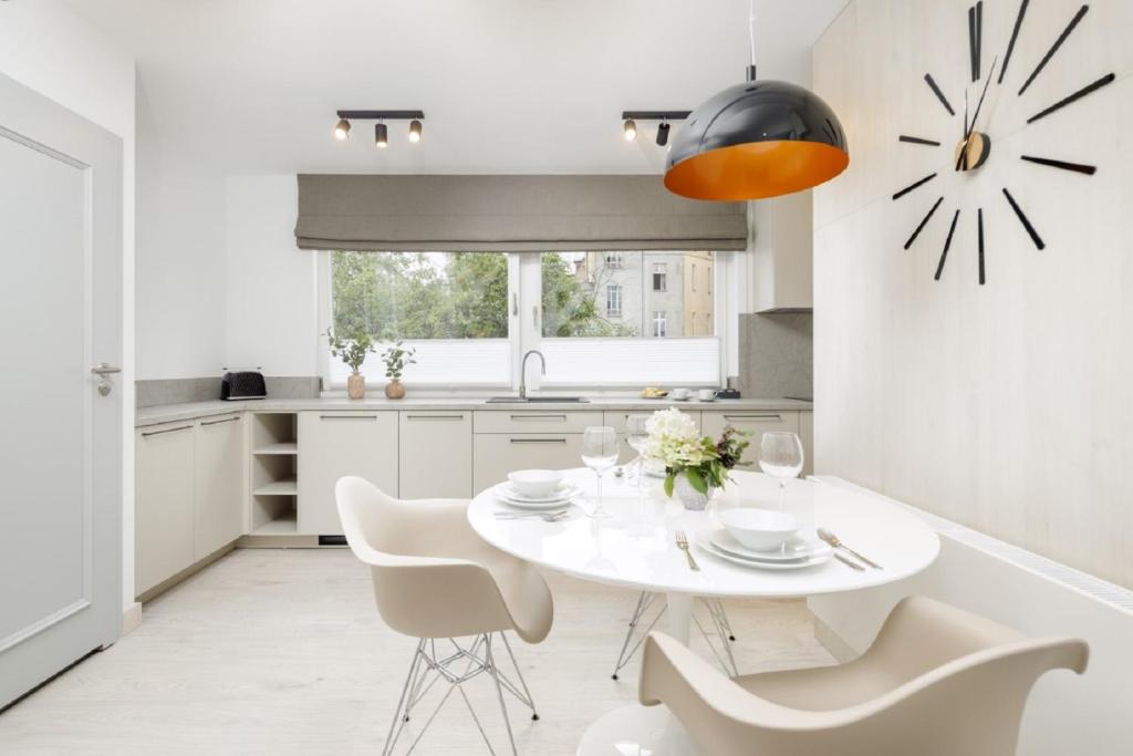 波兹南Apartamenty L11, Limanowskiego的白色的厨房配有白色的桌子和椅子