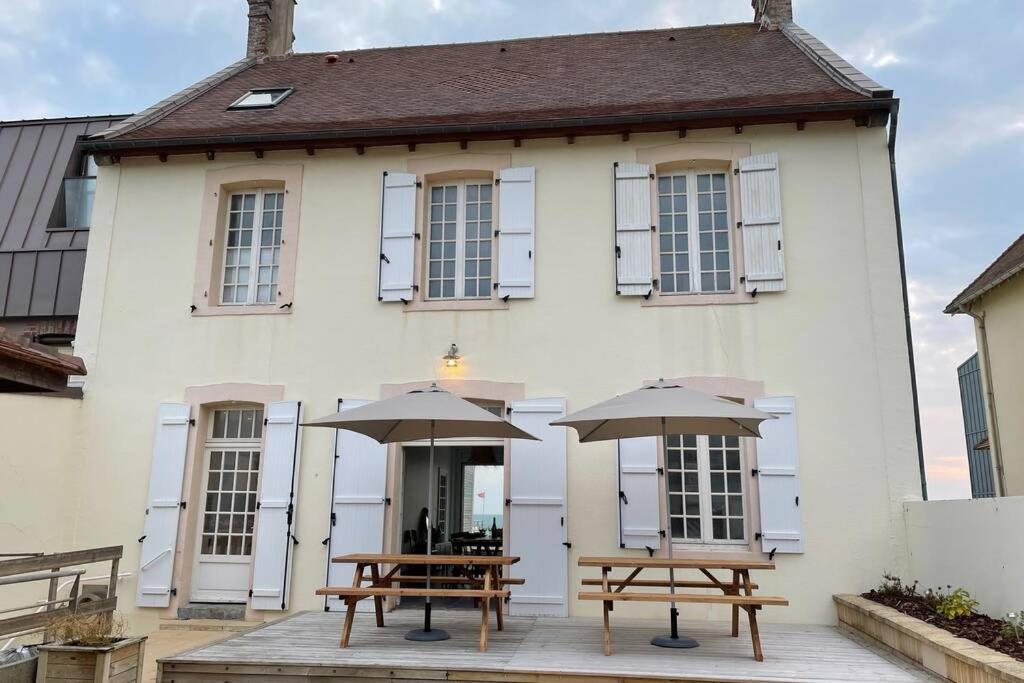 阿贡库坦维尔Agon-Coutainville, villa bord de mer的大楼前的两张带雨伞的野餐桌