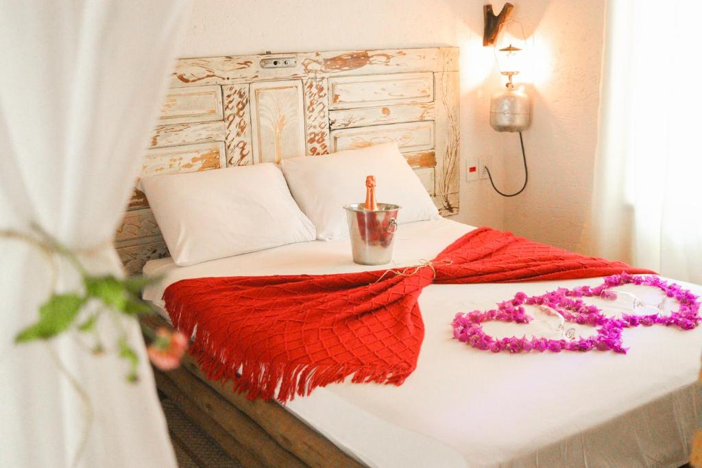 卡罗莱纳Rancho das Estrelas的一张带红色毯子和项链的床