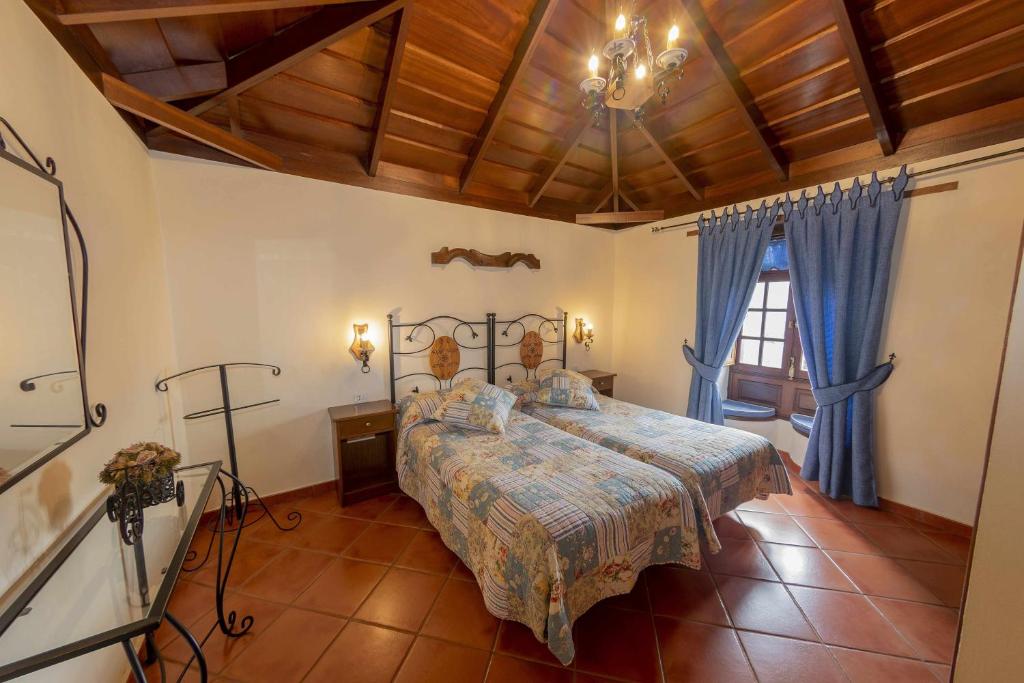洛西洛斯蒙特德尔阿古拉乡村旅馆的一间设有床铺的卧室,位于带蓝色窗帘的房间