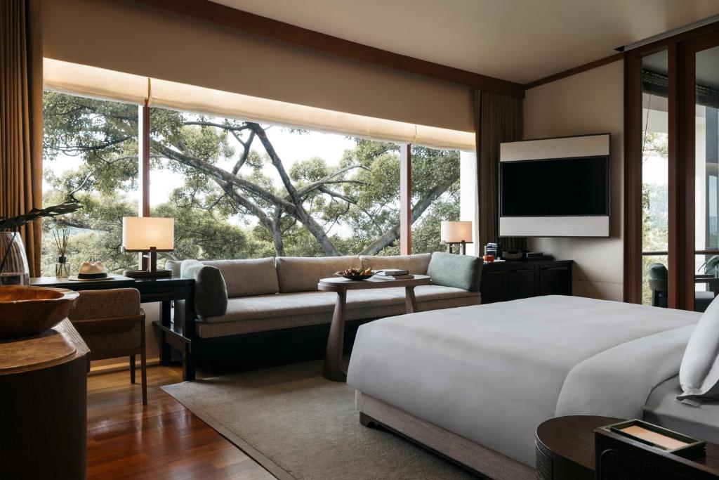 新加坡Capella Singapore的一间卧室配有一张床、一张沙发和一个大窗户