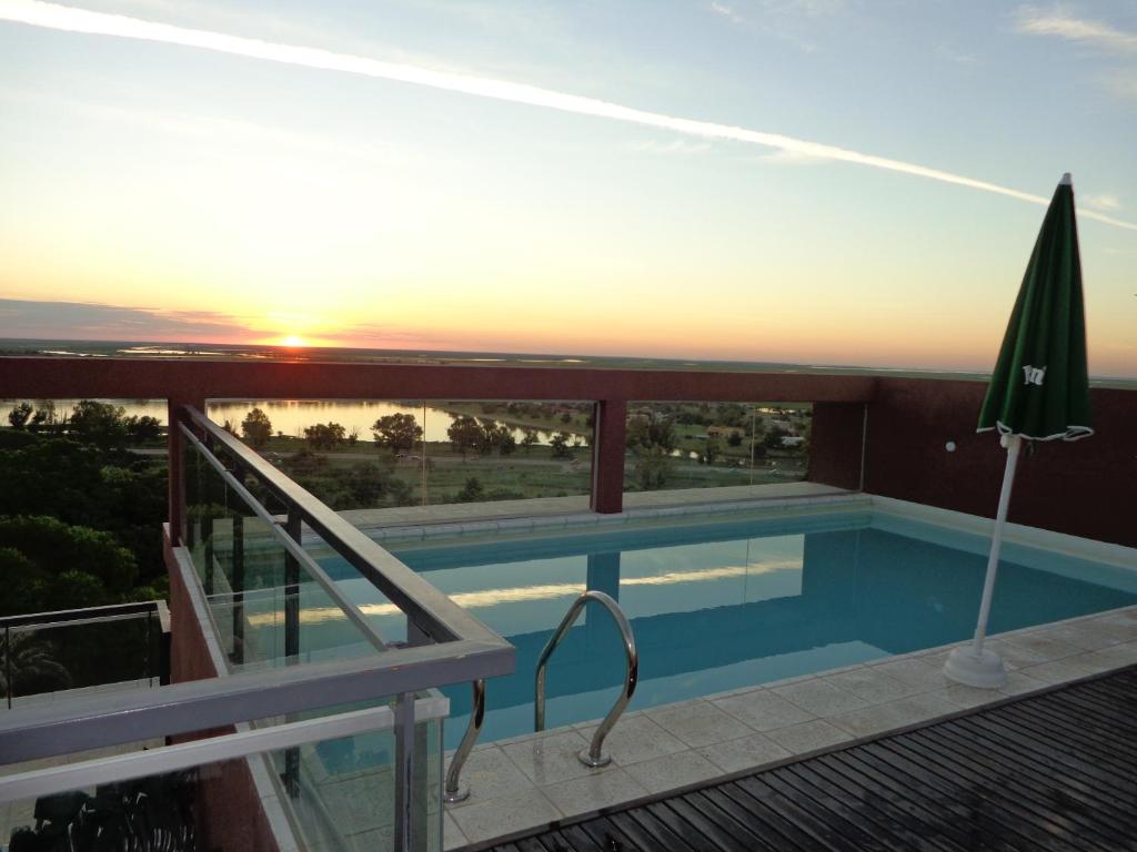 维多利亚Rio Manso Apart Hotel的一座享有日落美景的建筑屋顶上的游泳池