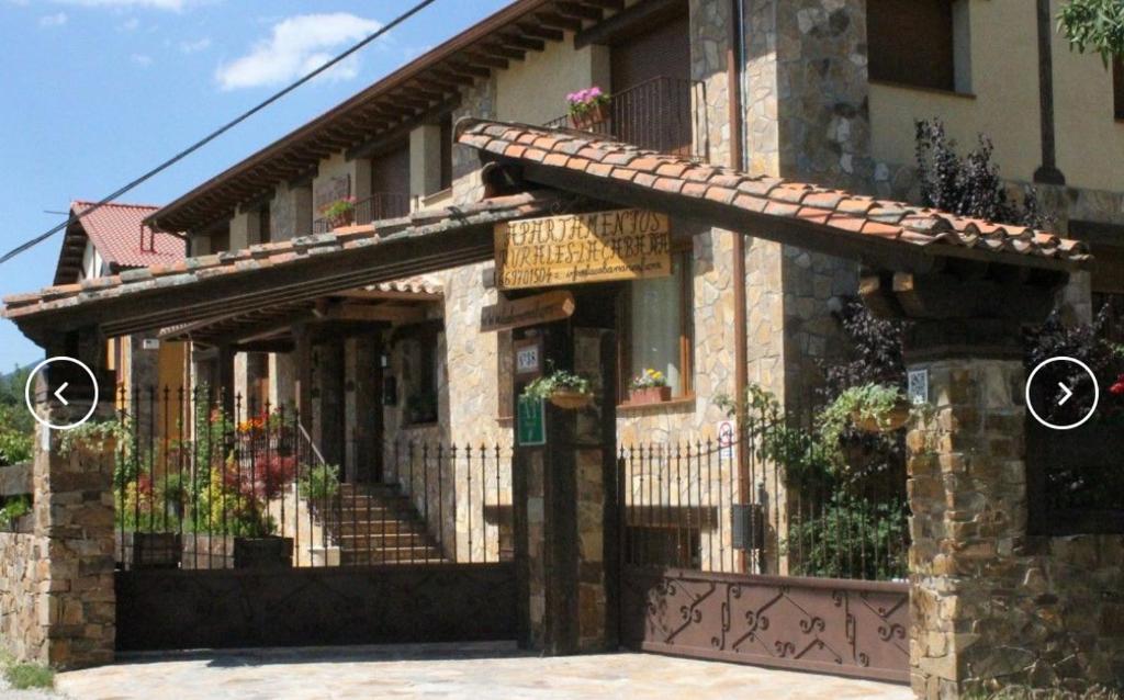 拉斯卡弗里亚Apartamentos Rurales "La Cabaña"的一座带围栏和鲜花门的建筑