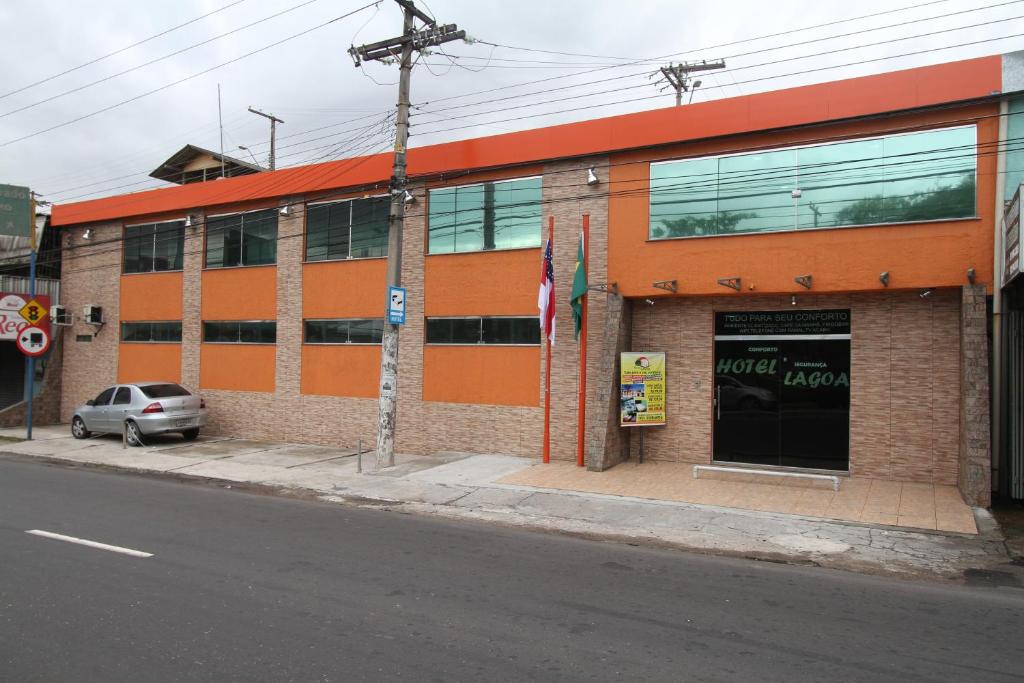 马瑙斯拉戈阿酒店的一座橙色的建筑,前面有停车位