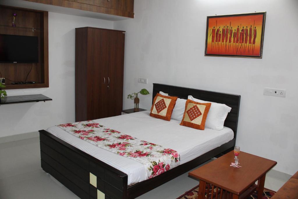 钦奈Friendlystay - An Home Stay And Elite的一间卧室配有一张床、一张桌子和一台电视。