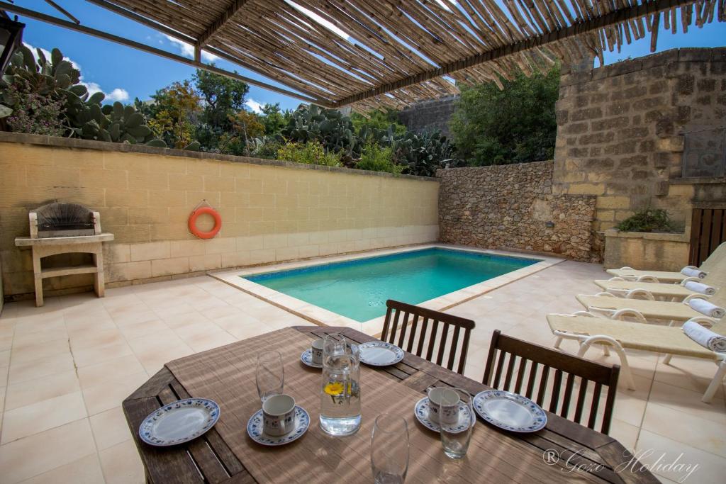 沙拉Ta Guzeppi Xaghra的一个带桌子和游泳池的庭院