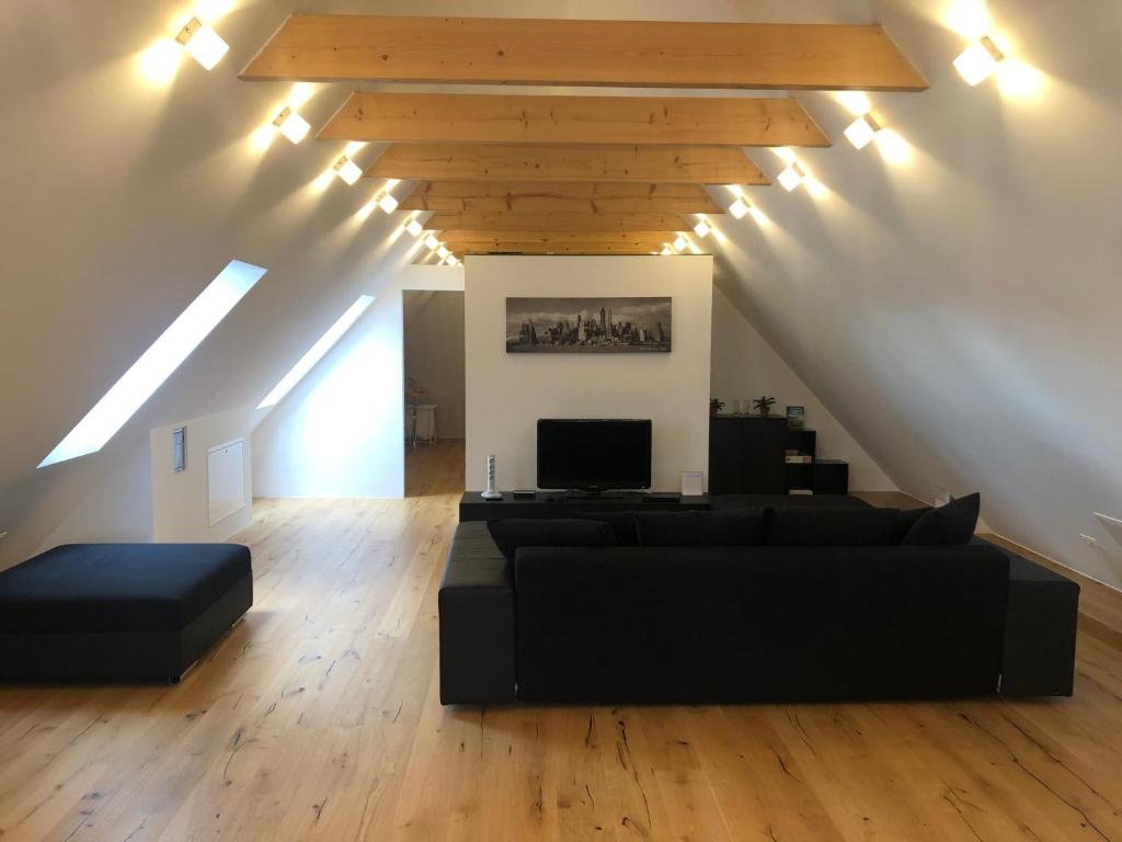 多瑙河畔克雷姆斯Loft Dachsberg的客厅设有黑色沙发和木制天花板。