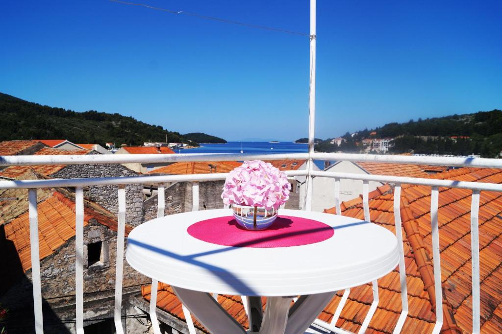 尼亚卢卡Art Apartment的阳台上的白色桌子上摆放着粉红色的鲜花