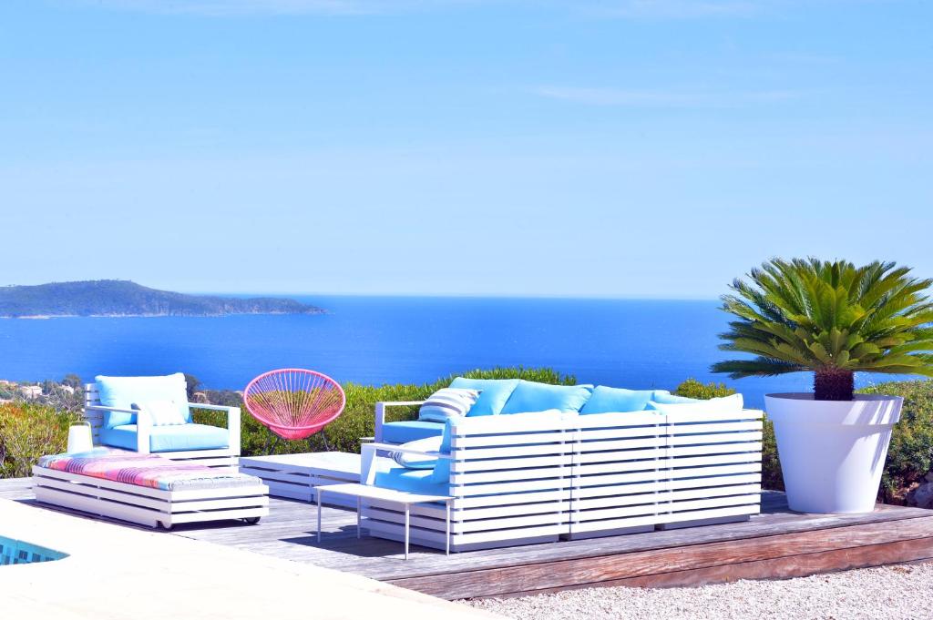 滨海卡瓦莱尔VILLA JUCANOS - Vue mer panoramique Golfe de St-Tropez的配有蓝色和白色家具的庭院和海洋