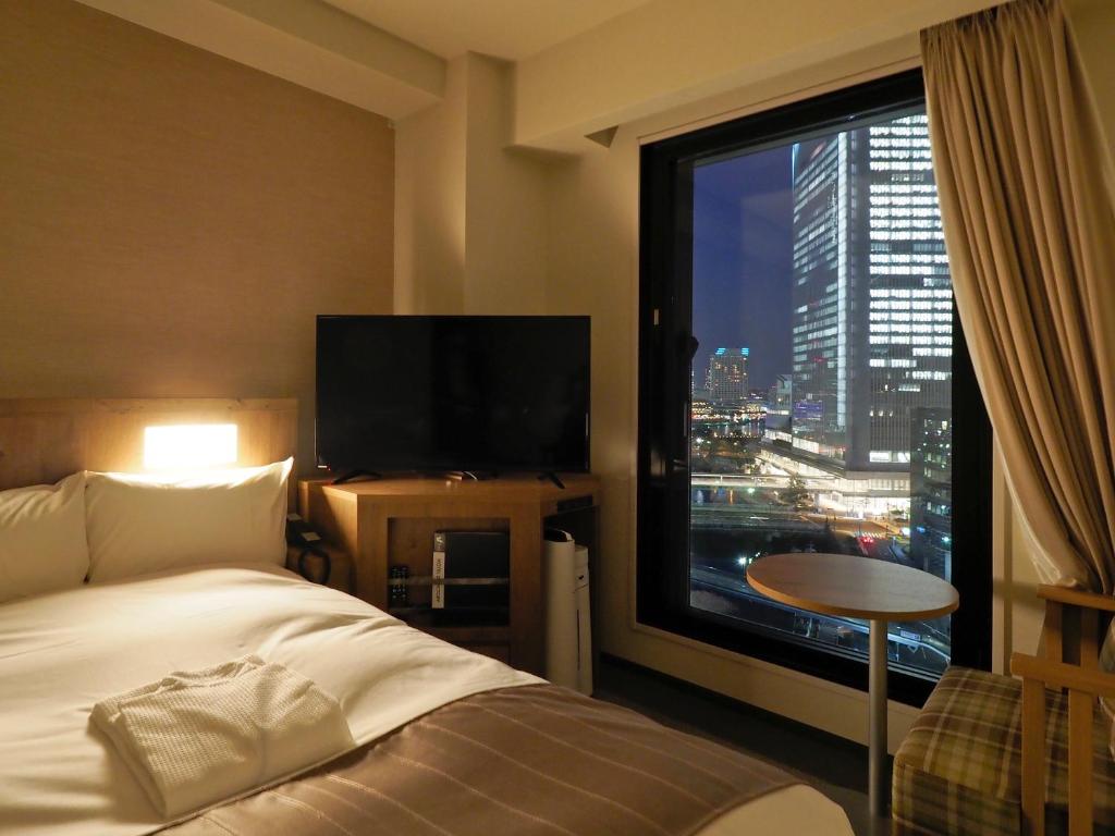 横滨Far East Village Hotel Yokohama的酒店客房设有一张床和一个大窗户