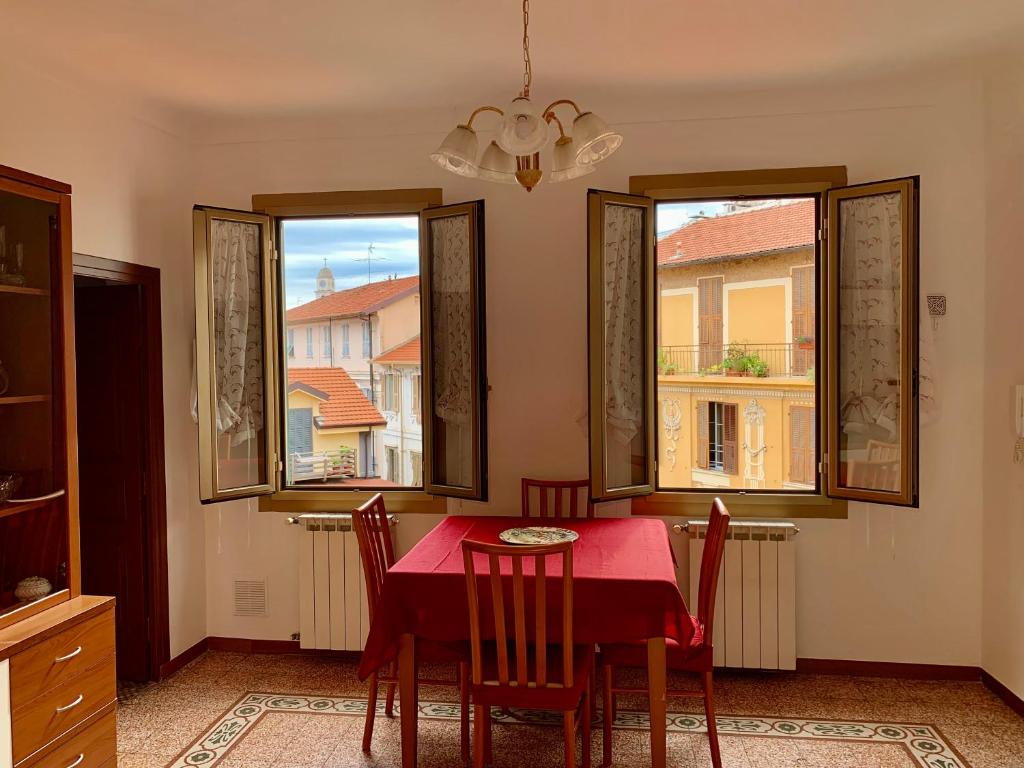 圣雷莫Casa Dei Nonni的一间用餐室,配有红色的桌子和椅子以及2扇窗户
