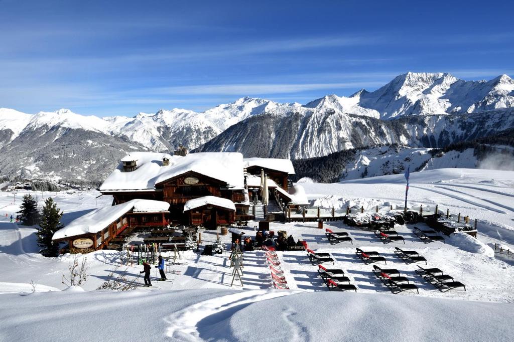 谷雪维尔Hôtel 3 étoiles -Restaurant Le Pilatus Courchevel的雪地里停有车辆的滑雪小屋