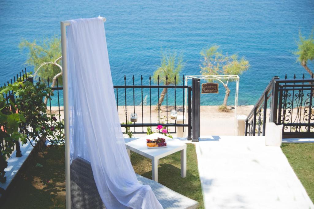 斯卡拉马里昂Maistrali Pension的一个带白色窗帘和桌子的庭院,享有海景