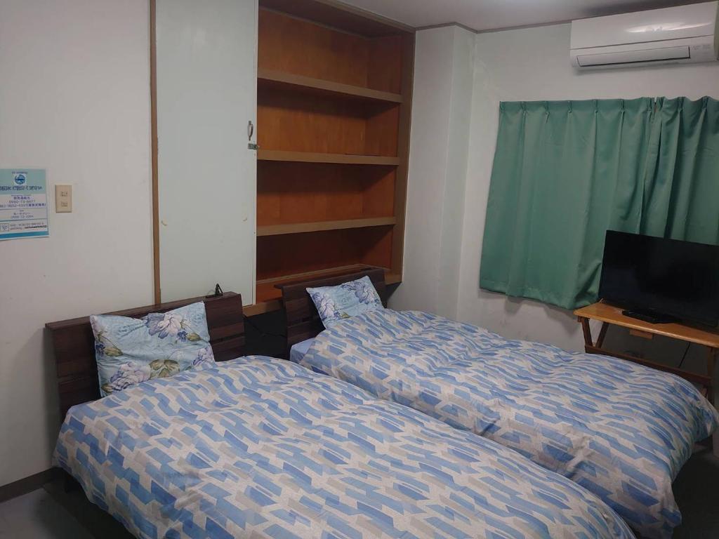 宫古岛ジンジャー的一间卧室配有两张床和电视。