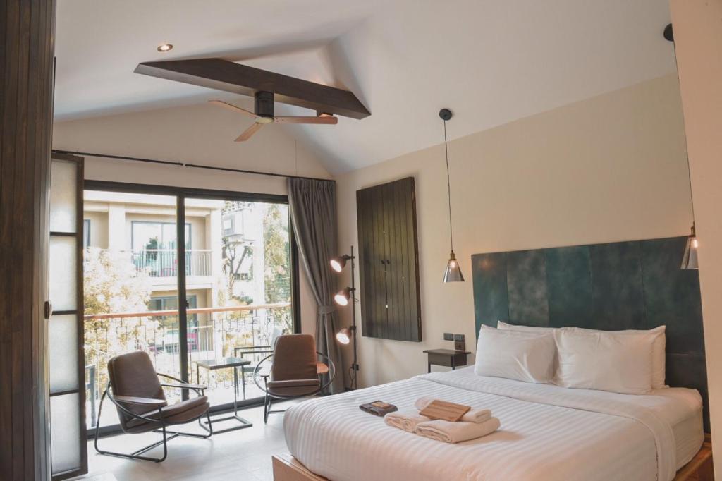 清迈盖特佳村酒店的一间卧室配有一张床,阳台配有椅子