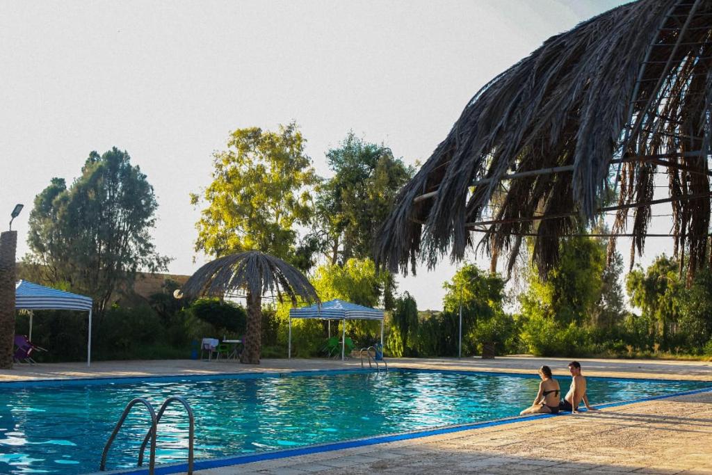 Al Azraq ash ShamālīAzraq Rest House的两名女性坐在度假村的游泳池里